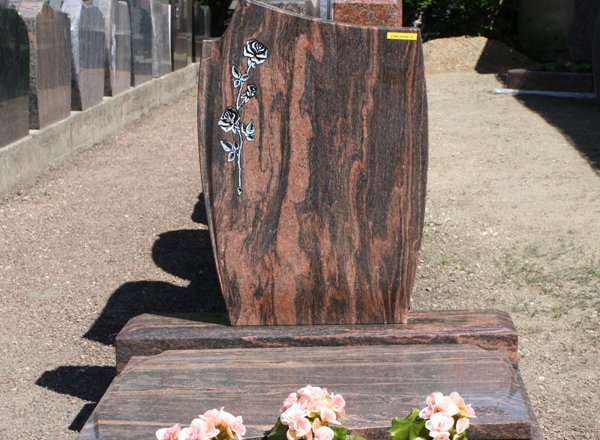 Stehende Grabstele aus rötlichem Granit mit gravierter Rose